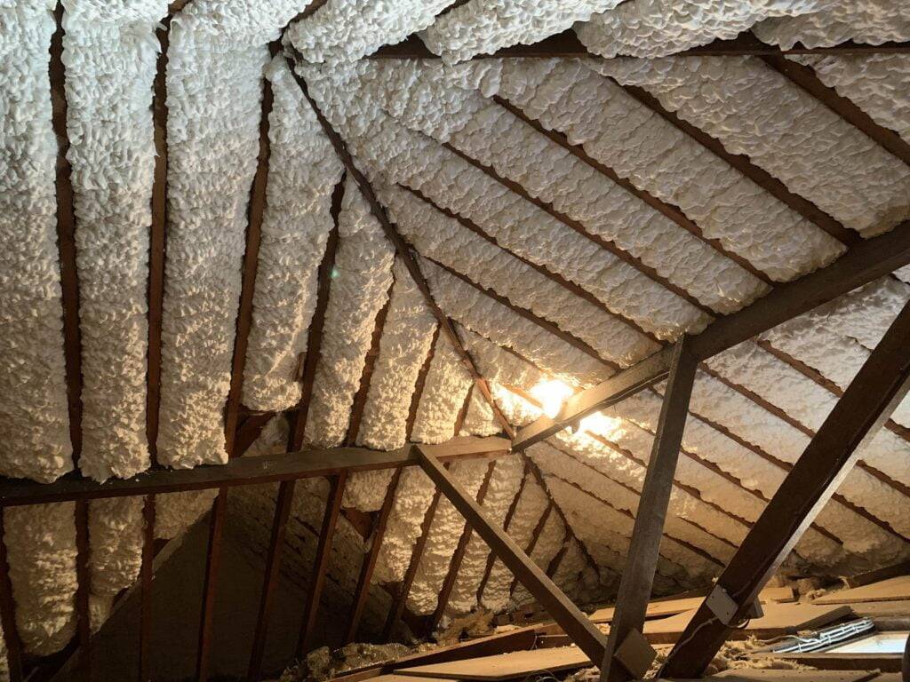 Open-cell spray polyurethane foam applied to the underside of a roof deck between rafters