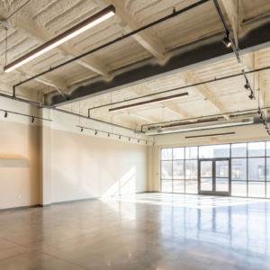 Finished open-ceiling retail interior with polished concrete floor, exposed steel beams, and spray foam insulation applied smoothly to the underside of the roof deck, highlighting how spray foam insulation can serve as both an energy-efficient and architectural ceiling finish.