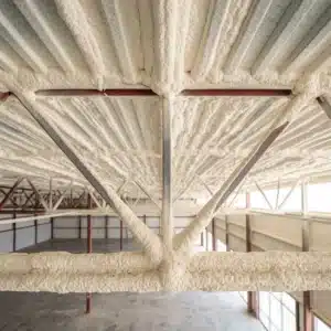 Church insulation: cream sprayed foam insulation covering a metal roof deck and wrapping the steel bar joists above a worship space